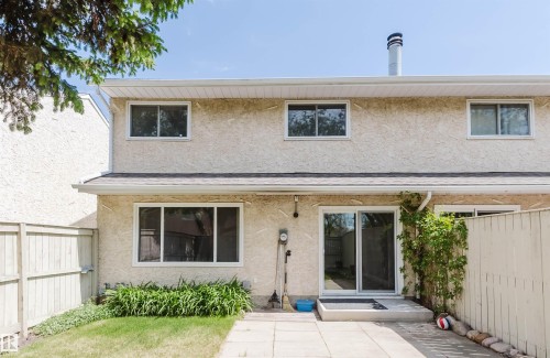 Rear exterior featuring a stucco finish, ground-level patio, sliding glass door, and fenced yard - 134 Callingwood Place Nw, Edmonton, AB - Outdoor With Exterior