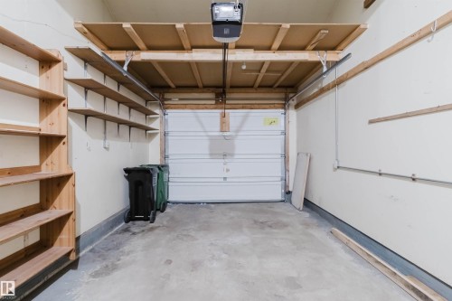 Garage with a concrete floor, built-in wooden shelving, overhead storage racks, and a white panel garage door - 134 Callingwood Place Nw, Edmonton, AB - Indoor Photo Showing Garage