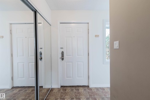Entryway featuring wood-finish flooring, a white panel door, and a mirrored sliding closet door - 134 Callingwood Place Nw, Edmonton, AB - Indoor Photo Showing Other Room