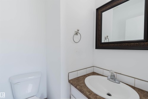 White vanity cabinet with a brown countertop, white drop-in sink, and a chrome faucet - 134 Callingwood Place Nw, Edmonton, AB - Indoor Photo Showing Bathroom