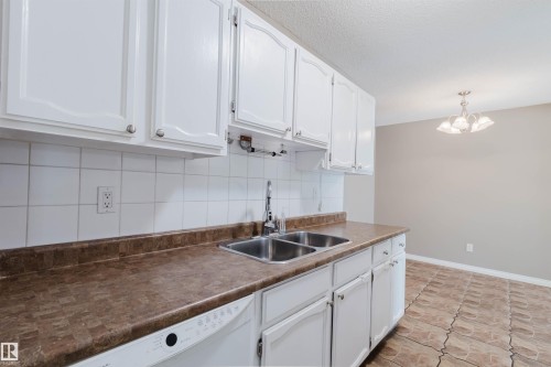 Kitchen featuring white cabinetry, a double basin stainless steel sink, a dishwasher, and a brown patterned countertop - 134 Callingwood Place Nw, Edmonton, AB - Indoor Photo Showing Kitchen With Double Sink