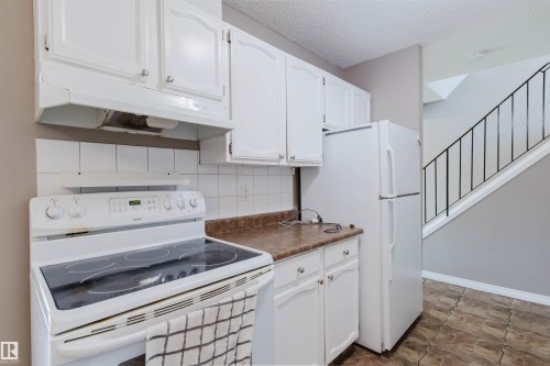 Kitchen area featuring white cabinetry, a white electric range with a smooth cooktop, white refrigerator, and a brown countertop - 134 Callingwood Place Nw, Edmonton, AB - Indoor Photo Showing Kitchen