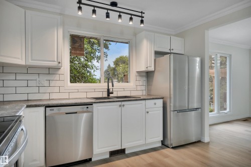 Kitchen featuring white shaker-style cabinetry with chrome hardware, subway tile backsplash, and dark countertops - 3607 53 Street, Wetaskiwin, AB - Indoor Photo Showing Kitchen With Double Sink