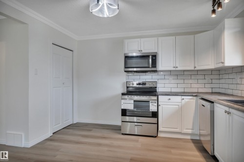 Kitchen featuring stainless steel appliances, white cabinetry, subway tile backsplash, and wood-finish flooring - 3607 53 Street, Wetaskiwin, AB - Indoor Photo Showing Kitchen