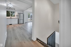 Kitchen with white shaker cabinetry, stainless steel refrigerator, and wood-finish flooring - 