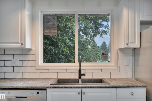 Kitchen sink area featuring a dual-basin sink with a matte black faucet, white shaker-style cabinetry, and a white subway tile backsplash - 3607 53 Street, Wetaskiwin, AB - Indoor Photo Showing Kitchen With Double Sink