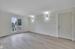 Room featuring light wood-finish flooring, white walls, and a large picture window - 