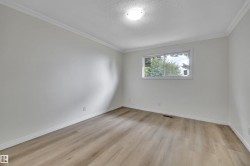 Room featuring light wood-finish flooring, white baseboards, white walls, and white crown molding - 