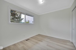 Spacious room featuring wood-finish flooring, white baseboards, and a window with white trim - 