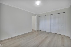 Spacious room featuring light wood-finish flooring, light gray walls, and white crown molding - 