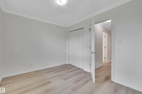 Interior room featuring wood-finish flooring, white baseboards, and crown molding - 3607 53 Street, Wetaskiwin, AB - Indoor Photo Showing Other Room