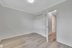Interior room featuring wood-finish flooring, white baseboards, and crown molding - 
