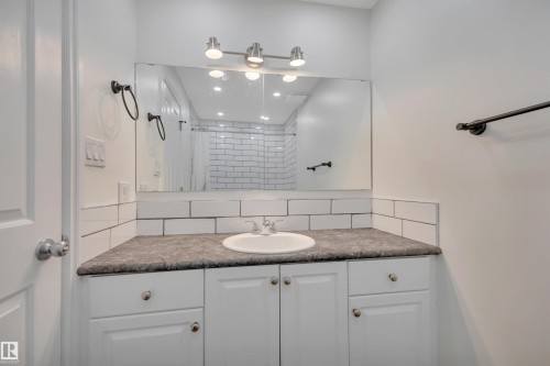 Bathroom vanity with a white integrated sink, dark countertop, and white cabinetry - 3607 53 Street, Wetaskiwin, AB - Indoor Photo Showing Bathroom