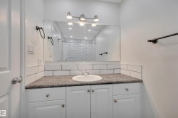 Bathroom vanity with a white integrated sink, dark countertop, and white cabinetry - 