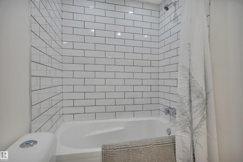 White subway tile shower surround with dark grout, white bathtub, and chrome fixtures - 3607 53 Street, Wetaskiwin, AB - Indoor Photo Showing Bathroom