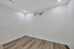 Neutral white wall finishes with recessed lighting and wood-finish flooring - 