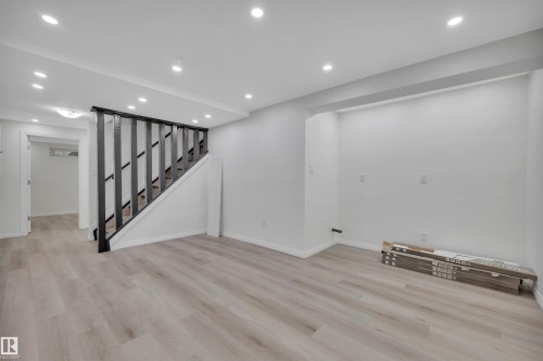 Light wood-finish flooring throughout, complemented by a contemporary black staircase railing and recessed ceiling lighting - 3607 53 Street, Wetaskiwin, AB - Indoor Photo Showing Other Room