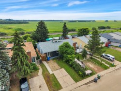 Single-story residence featuring dark siding, a light gray roof, and a paved driveway - 