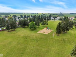 Expansive green space featuring a dedicated playground area with sand base, swings, and colorful play equipment - 