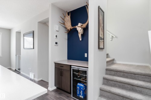Built-in beverage station featuring dark wood-finish cabinetry, a light-toned countertop, and an integrated beverage refrigerator - 3456 Cutler Crescent Sw, Edmonton, AB - Indoor Photo Showing Other Room