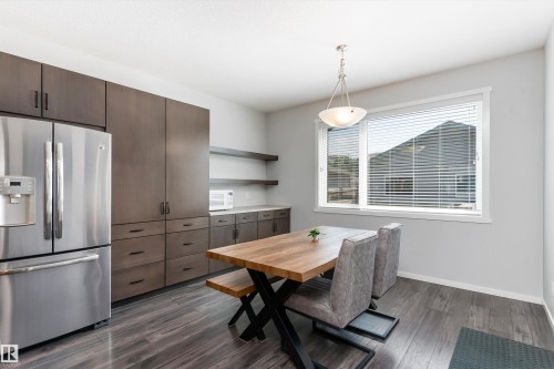 Open-concept dining area featuring wood-finish flooring, a contemporary window with blinds, and a modern pendant light fixture - 3456 Cutler Crescent Sw, Edmonton, AB - Indoor