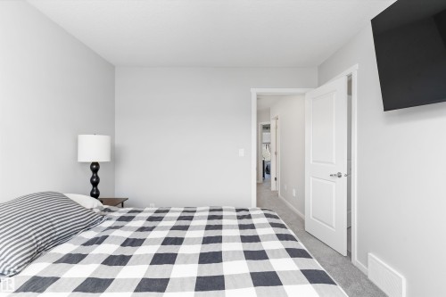 Carpeted room featuring a neutral color palette, recessed baseboards, and a paneled interior door with chrome hardware - 3456 Cutler Crescent Sw, Edmonton, AB - Indoor Photo Showing Bedroom