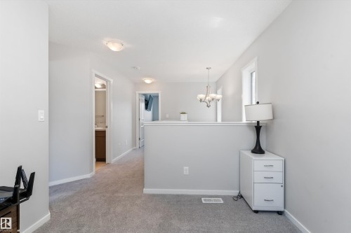 Carpeted hallway featuring light gray walls, white trim, and flush-mount ceiling lighting - 3456 Cutler Crescent Sw, Edmonton, AB - Indoor