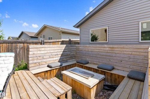 Backyard patio featuring built-in wooden bench seating, a stone-top fire pit, and privacy fencing - 3456 Cutler Crescent Sw, Edmonton, AB - Outdoor With Deck Patio Veranda With Exterior