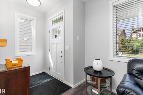Bright entry area featuring a white multi-pane door with transom window, wood-finish flooring, two large windows with blinds, and white trim throughout - 3456 Cutler Crescent Sw, Edmonton, AB - Indoor