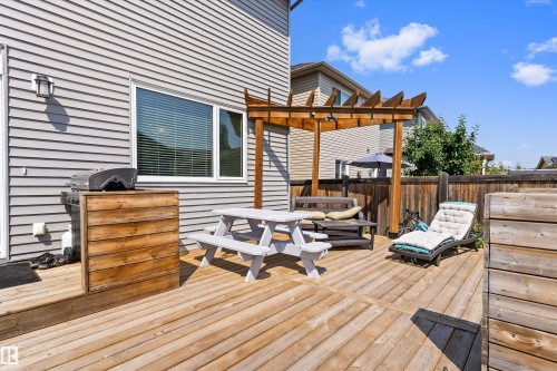 Spacious wooden deck with a built-in pergola, featuring a privacy fence, exterior siding, and a large window - 3456 Cutler Crescent Sw, Edmonton, AB - Outdoor With Deck Patio Veranda With Exterior