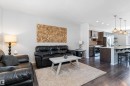 Open-concept living space featuring wood-finish flooring, a kitchen island with seating, pendant lighting, stainless steel appliances, and dark wood cabinetry - 3456 Cutler Crescent Sw, Edmonton, AB  - Indoor Photo Showing Living Room 