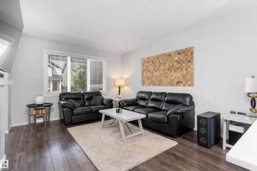 Spacious living area featuring wood-finish flooring, light-toned walls, and a large window with blinds - 3456 Cutler Crescent Sw, Edmonton, AB - Indoor Photo Showing Living Room