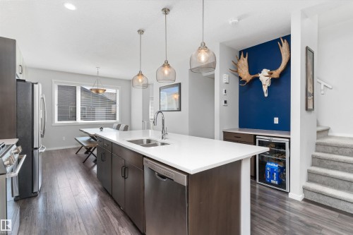 Kitchen featuring a large island with white countertop, integrated sink, and stainless steel dishwasher - 3456 Cutler Crescent Sw, Edmonton, AB - Indoor Photo Showing Kitchen With Double Sink With Upgraded Kitchen