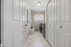 Dedicated laundry area featuring front-loading washer and dryer, tile-patterned flooring, window with blinds, and white panel doors - 