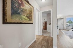 Hallway with wood-finish flooring, light neutral wall paint, and white trim - 