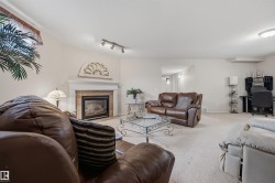 Expansive living area featuring a fireplace with a white mantel and a light-toned brick surround - 