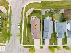 Overhead view of a residential property with a brown shingle roof, paved driveway, and established landscaping - 