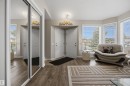 Entryway featuring wood-finish flooring, mirrored closet doors, and multiple windows - 28 Norfolk Close, St. Albert, AB 