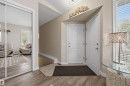Entryway featuring a white paneled door, ceramic tile flooring, and wood-finish flooring - 28 Norfolk Close, St. Albert, AB 