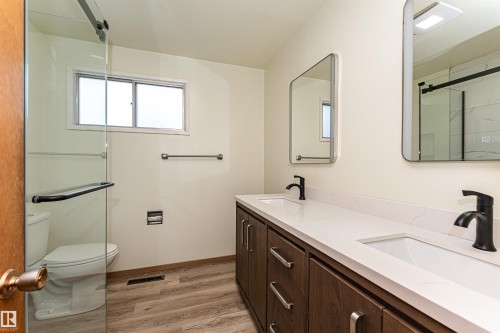 Modern bathroom featuring a dual vanity with white countertops, integrated sinks, and matte black fixtures - 4812 105B Street Nw, Edmonton, AB - Indoor Photo Showing Bathroom