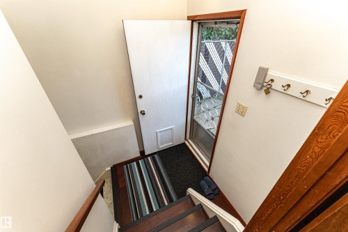 Entryway with wood-finish flooring, a white door with pet access, and a storm door - 4812 105B Street Nw, Edmonton, AB - Indoor Photo Showing Other Room