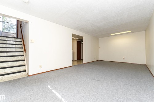 Spacious area with light gray carpeting, neutral wall finishes, and a recessed fluorescent light fixture - 4812 105B Street Nw, Edmonton, AB - Indoor Photo Showing Other Room