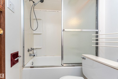 Bathtub with integrated shower, sliding glass door enclosure, and wall-mounted showerhead - 4812 105B Street Nw, Edmonton, AB - Indoor Photo Showing Bathroom