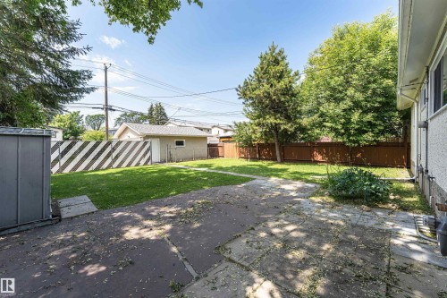 Expansive backyard featuring a concrete patio, a central lawn area, and mature perimeter trees - 4812 105B Street Nw, Edmonton, AB - Outdoor