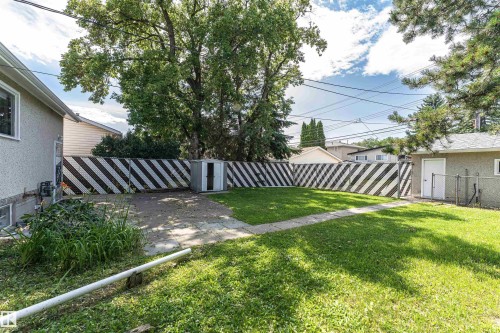 Expansive rear yard featuring a concrete pad, a compact shed, and established trees - 4812 105B Street Nw, Edmonton, AB - Outdoor