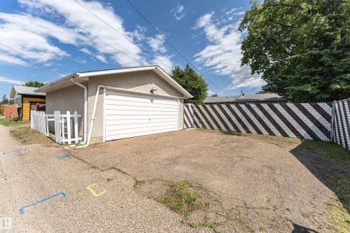 Detached garage with a white panel door, stucco exterior, and white rain gutters - 4812 105B Street Nw, Edmonton, AB - Outdoor