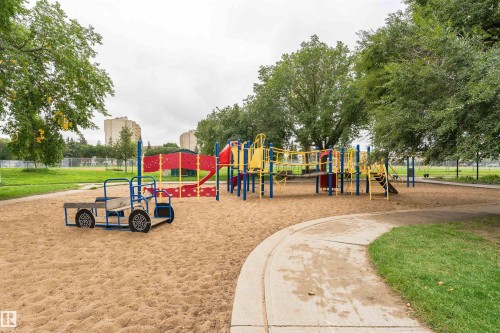 Community playground featuring multiple play structures, sand ground cover, mature trees, and concrete pathways - 4812 105B Street Nw, Edmonton, AB - Outdoor