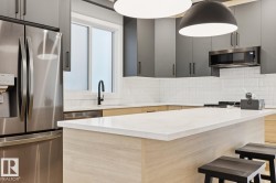 Modern kitchen featuring a white subway tile backsplash, light wood-finish lower cabinetry, and dark gray upper cabinetry - 