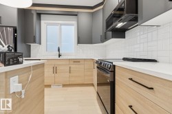 Modern kitchen featuring two-tone cabinetry with light wood-finish lower cabinets and dark gray upper cabinets - 