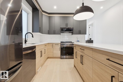 Modern kitchen featuring two-tone cabinetry with black upper cabinets and wood-finish lower cabinets - 10531 67 Avenue Nw, Edmonton, AB - Indoor Photo Showing Kitchen With Upgraded Kitchen
